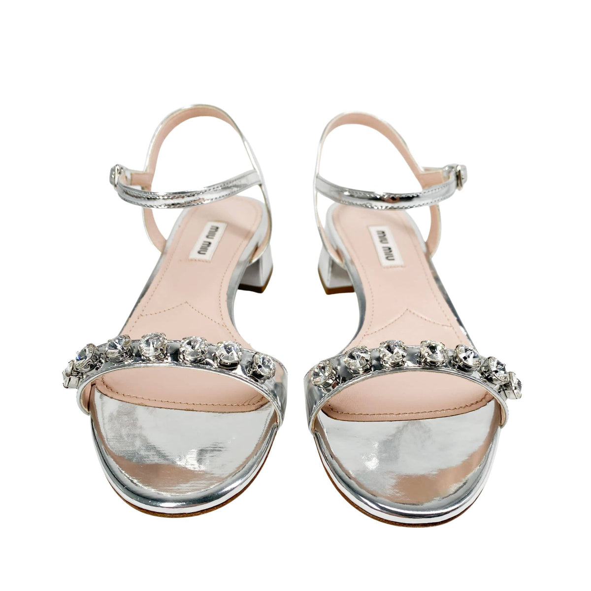 Front view of a pair of Miu Miu metallic silver leather sandals displaying sparkling crystal strap embellishments.