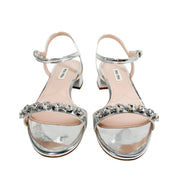 Front view of a pair of Miu Miu metallic silver leather sandals displaying sparkling crystal strap embellishments.