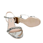 Bottom and sole profile view of Miu Miu crystal silver leather sandal showing logo branding and sturdy mid block heel.