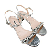 Three-quarter pair view of Miu Miu crystal-embellished silver leather open-toe sandals.