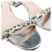 Close-up macro view of shimmering crystal embellishments across the front strap of Miu Miu silver leather sandals.