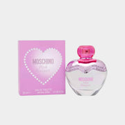 Moschino Pink Bouquet Eau de Toilette heart-shaped glass bottle displayed next to its pink heart-patterned retail box packaging.