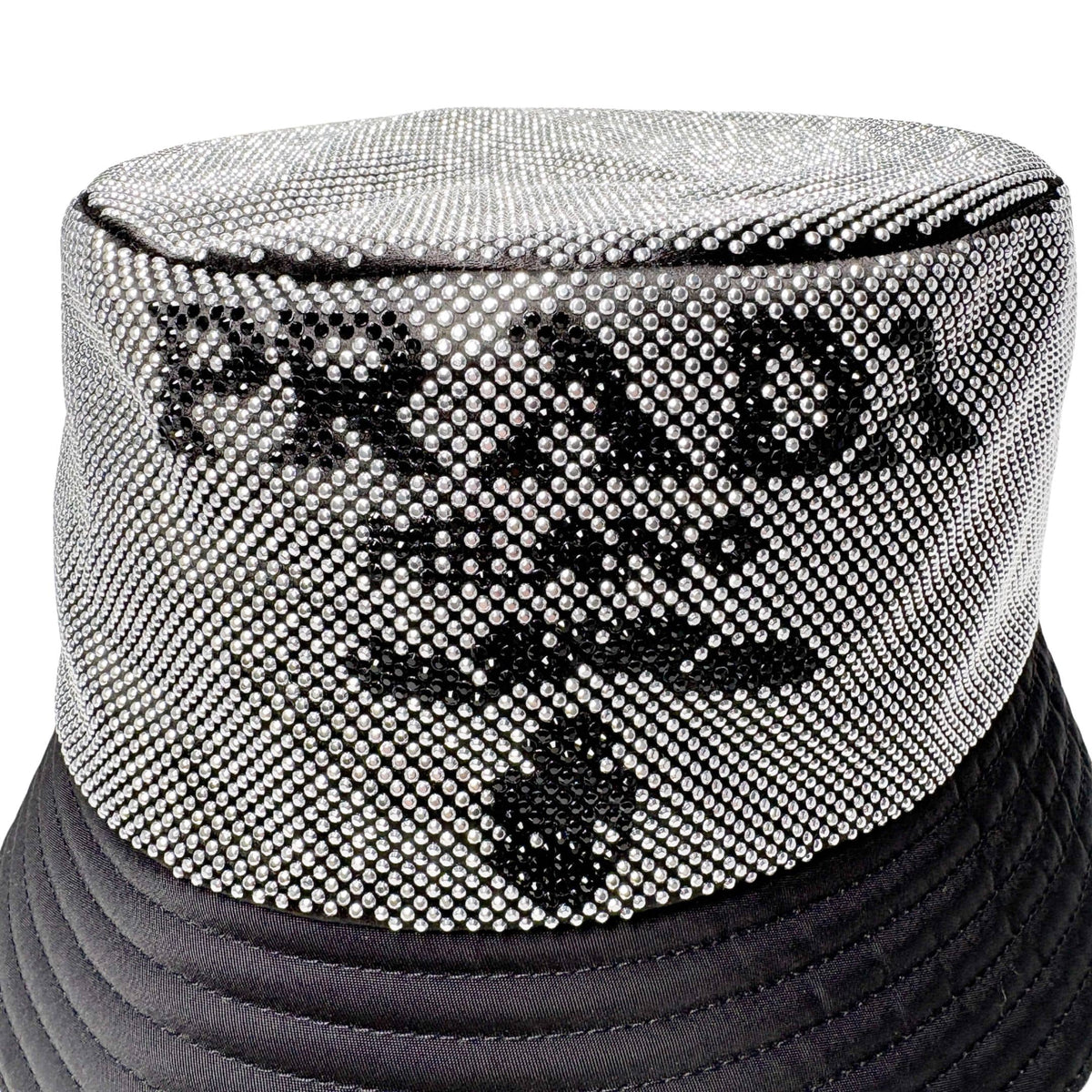 Close-up view of silver crystal Prada Milano logo detail on black nylon luxury bucket hat