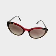 Prada women's tortoise shell sunglasses with red frame accent and gradient lenses on a white background