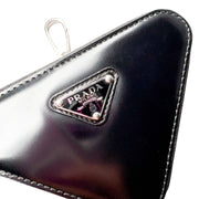 Close-up angled view of black Prada triangle coin pouch showing glossy spazzolato leather finish and zip closure