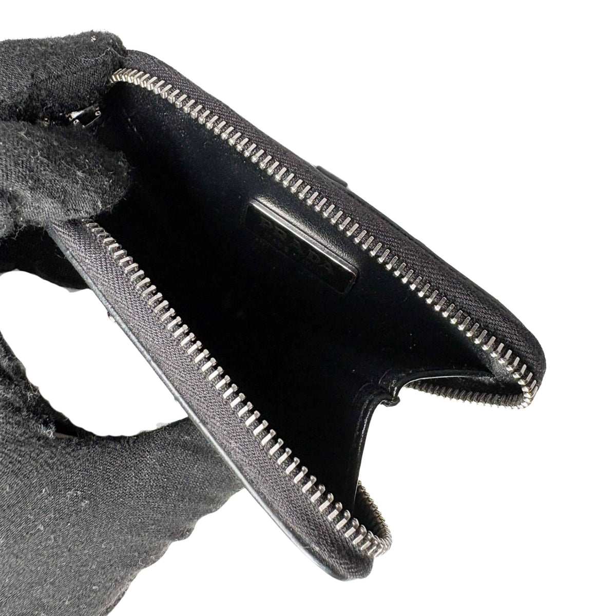 Open view of black Prada Spazzolato triangle coin pouch showing interior compartment and zipper detail