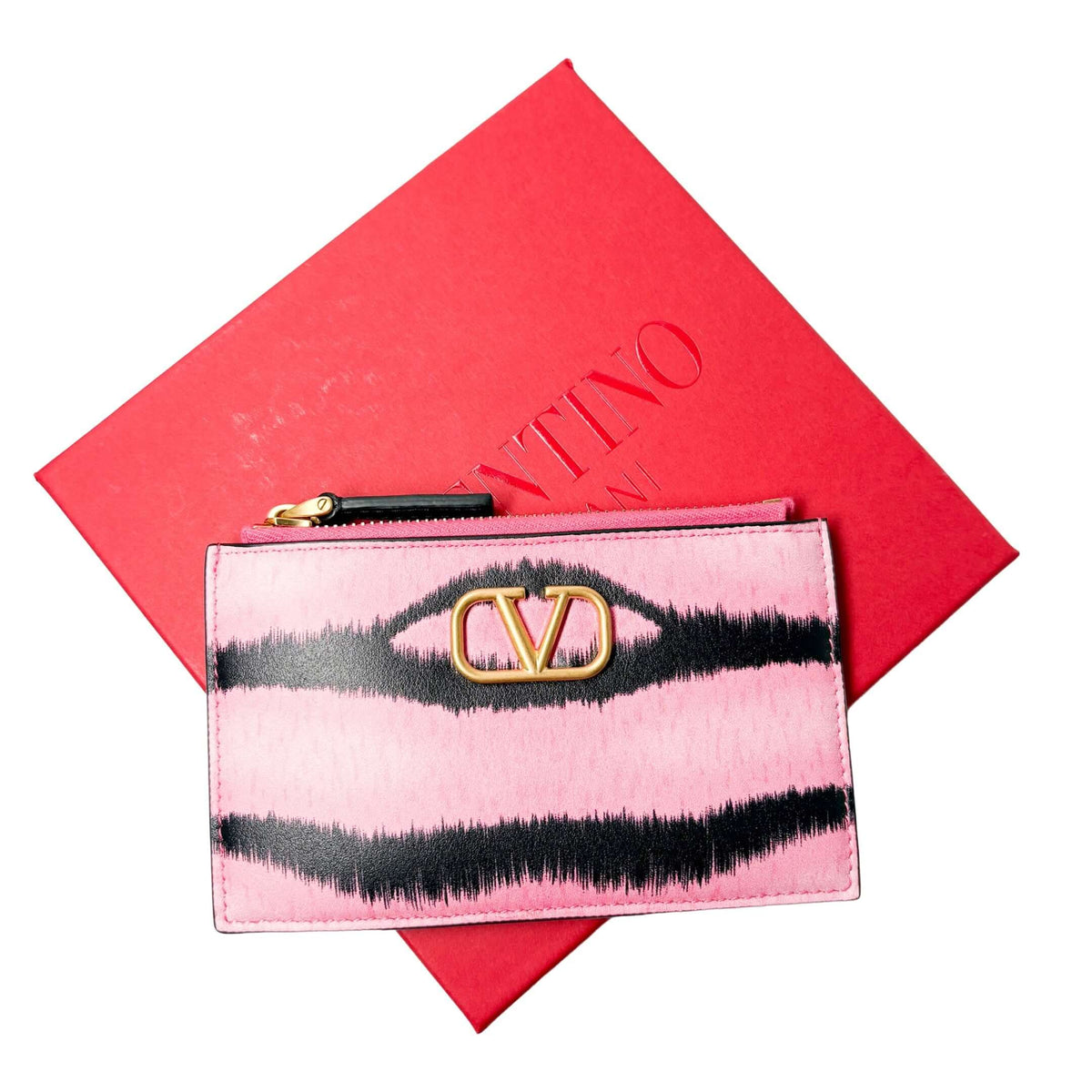 The pink and black striped Valentino V-Logo leather wallet displayed on top of its signature red Valentino gift box.