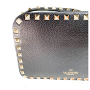 Frontal view of black Valentino Rockstud camera bag showing the gold clasp and perimeter stud border.