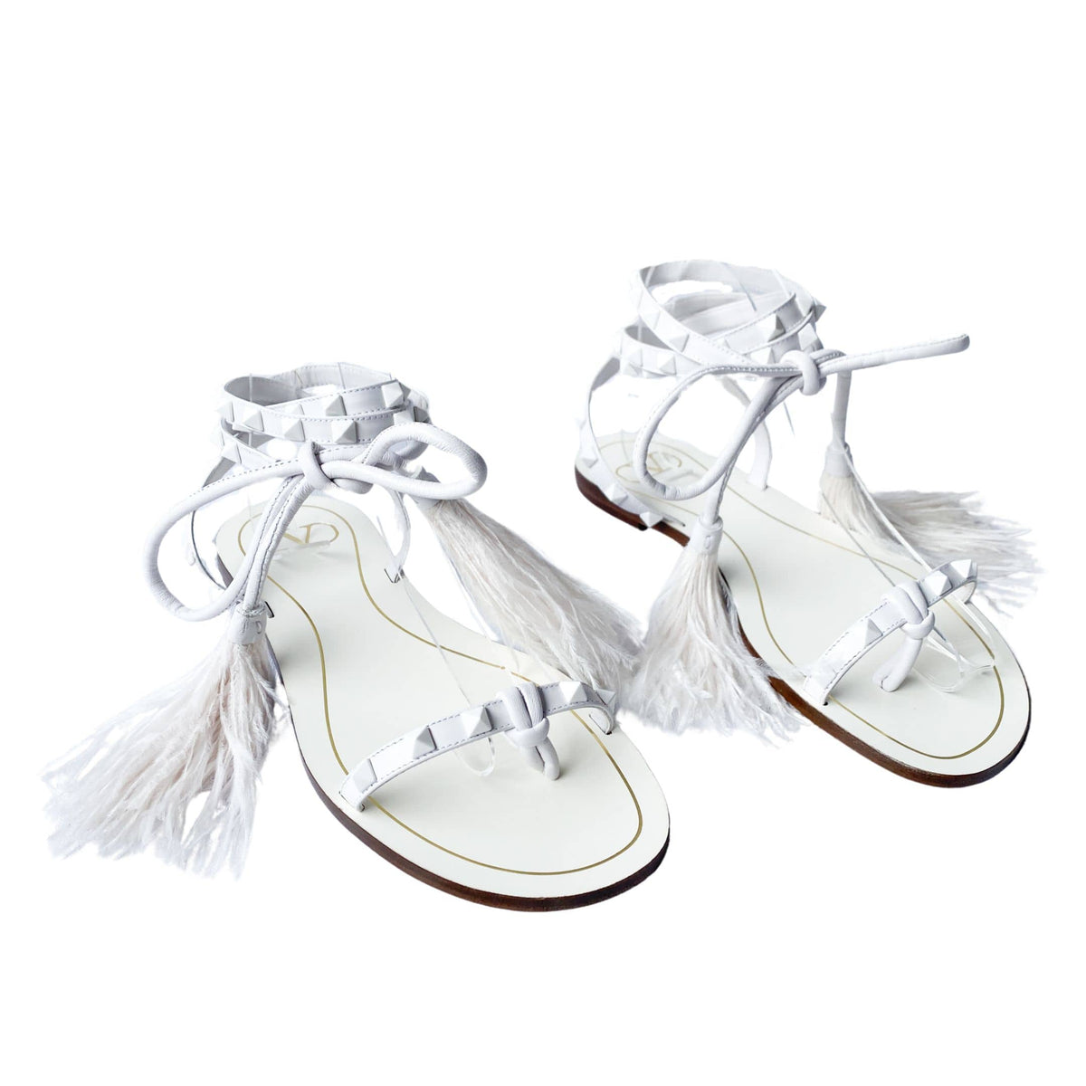 Top-angle pair view of white Valentino Garavani Flair flat sandals displaying delicate lace-up straps and feather trims.