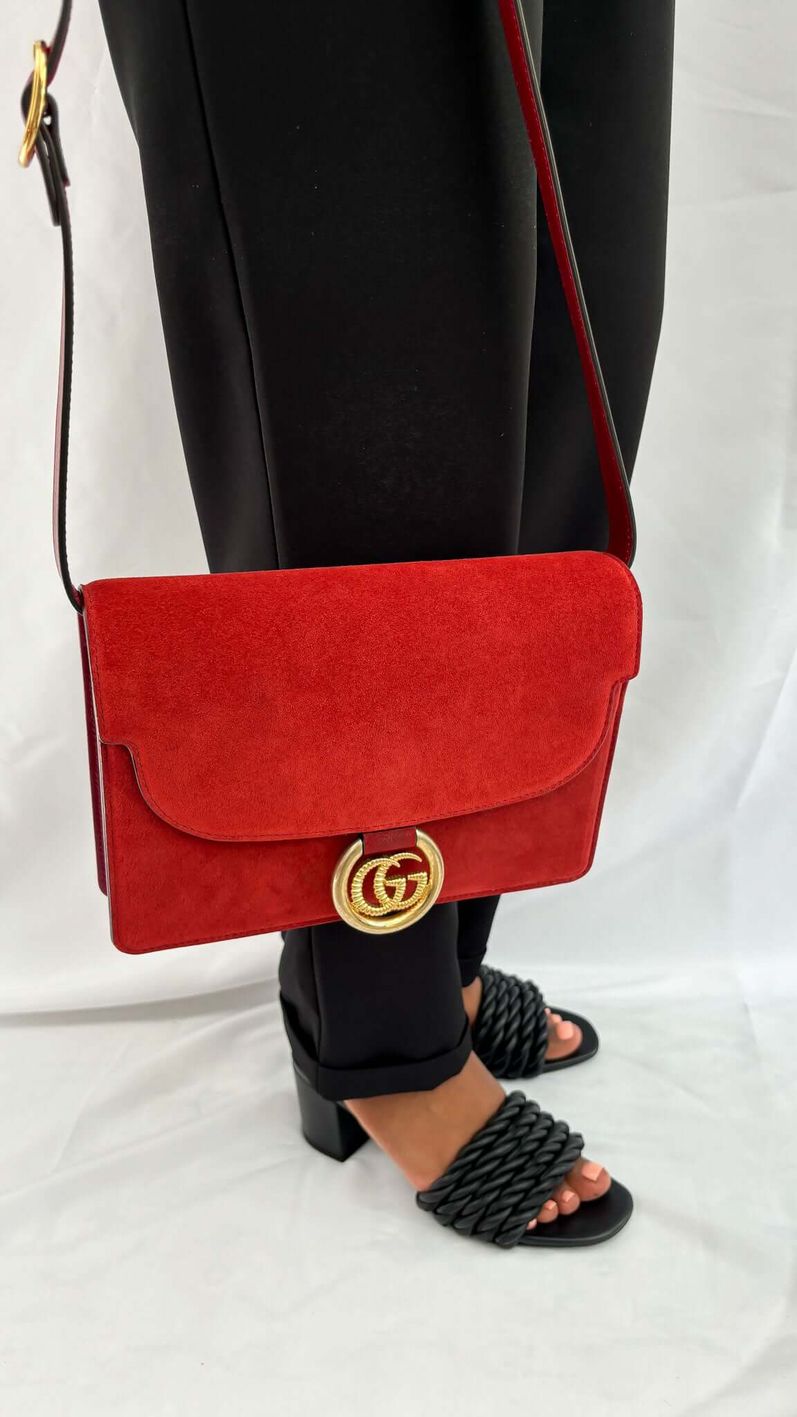 Model wearing Valentino black braided rope heel sandals styled with black pants and a red handbag.