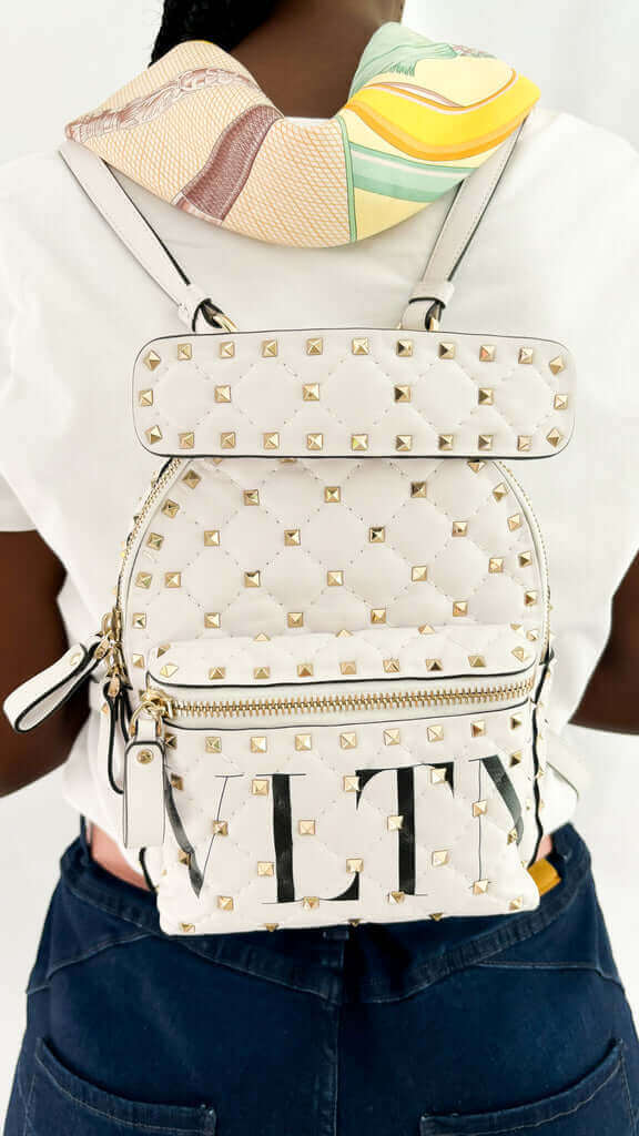 Model carrying the white Valentino Rockstud mini backpack on her back using dual shoulder straps.