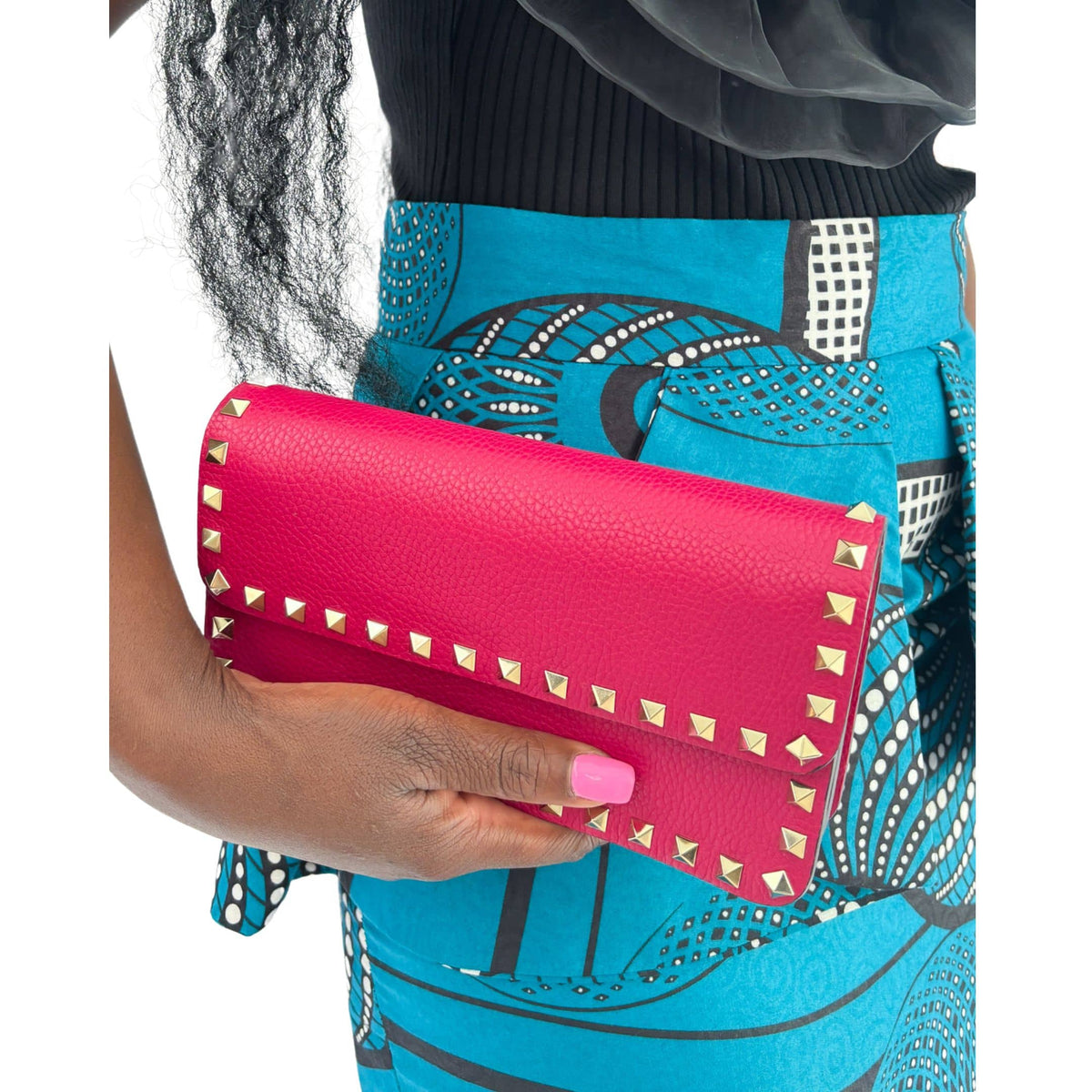 Model holding the hot pink Valentino Rockstud clutch under the arm in a lifestyle setting.