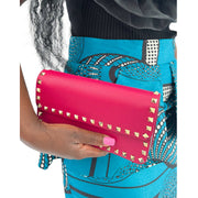 Model holding the hot pink Valentino Rockstud clutch under the arm in a lifestyle setting.