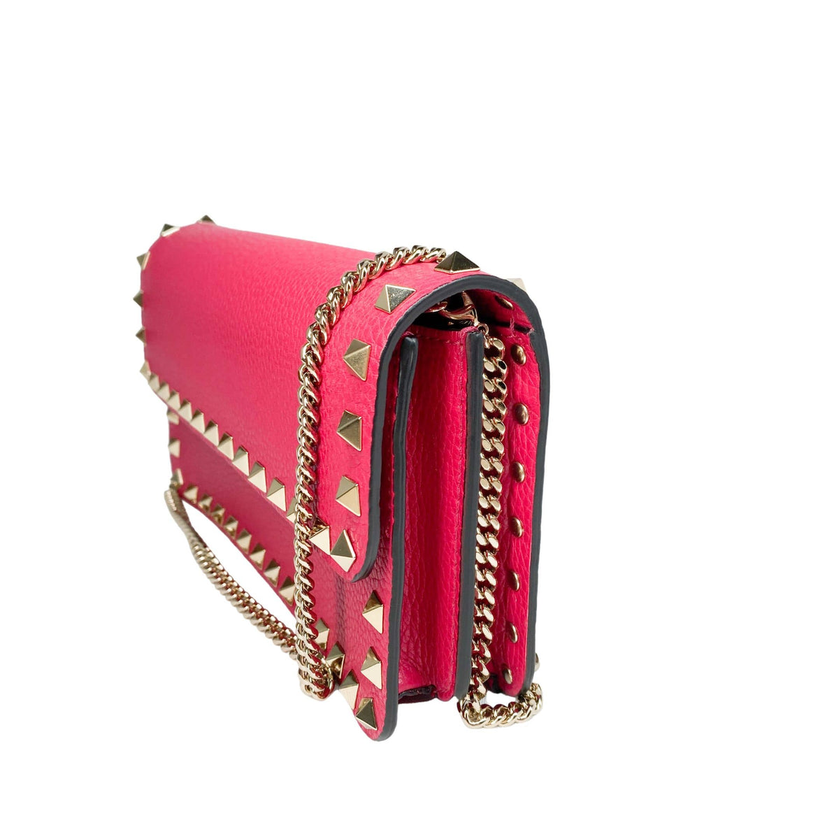 Side profile view of the hot pink Valentino Rockstud clutch showing side gussets and chain strap attachment.