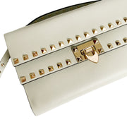 Angled top view of the cream Valentino clutch showcasing the gold lock clasp, studded strap, and flap closure.