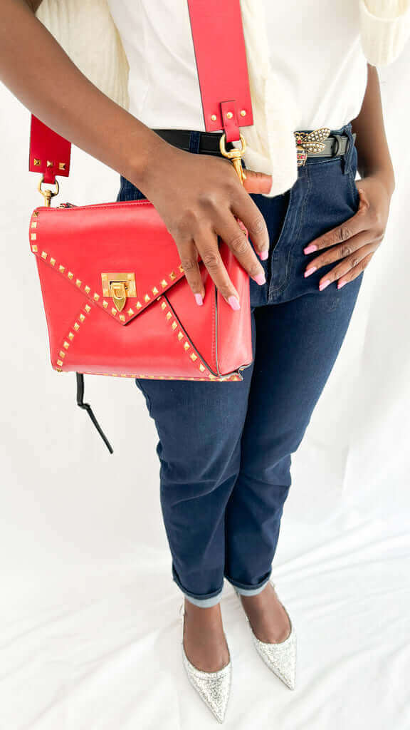 Close-up on-body view of the red Valentino Rockstud bag showcasing the wide shoulder strap and gold hardware accents.