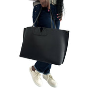 Model carrying the black leather Valentino V Tote Bag over the shoulder in a lifestyle setting.