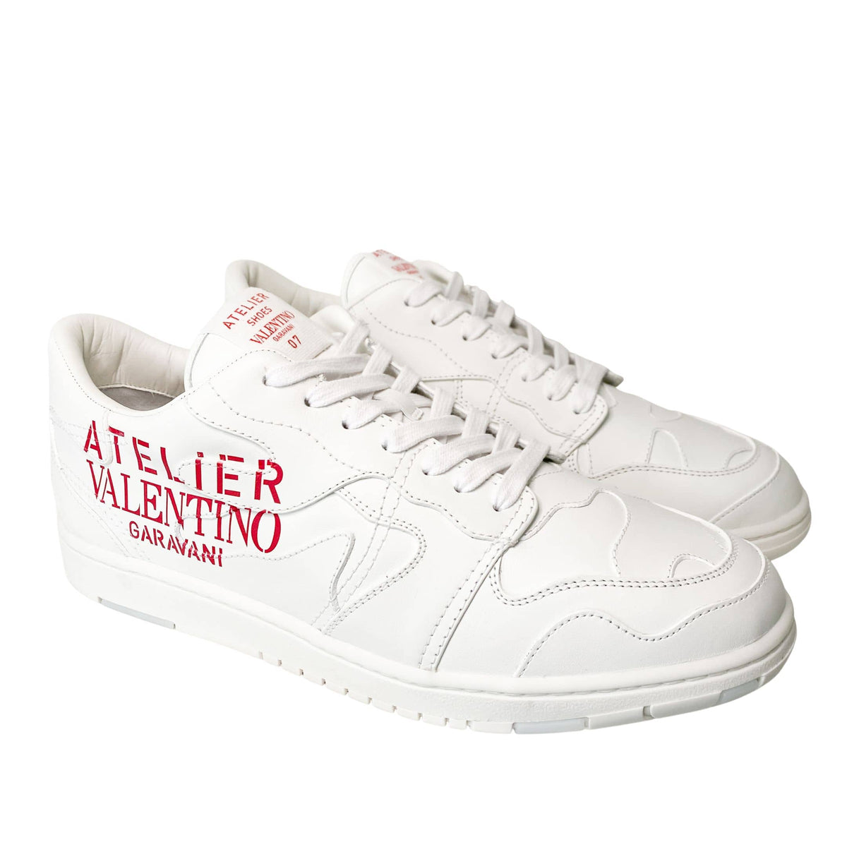 Angled front view of white Valentino Atelier trainers showing lace-up closure and toe cap.