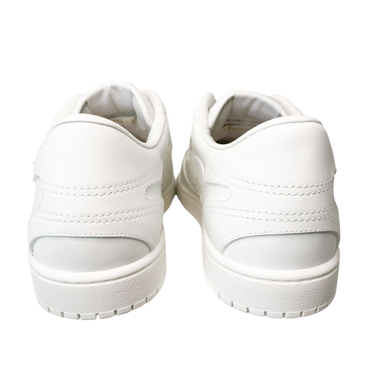 Back view of white Valentino leather sneakers showing structured heel counters and thick rubber soles.