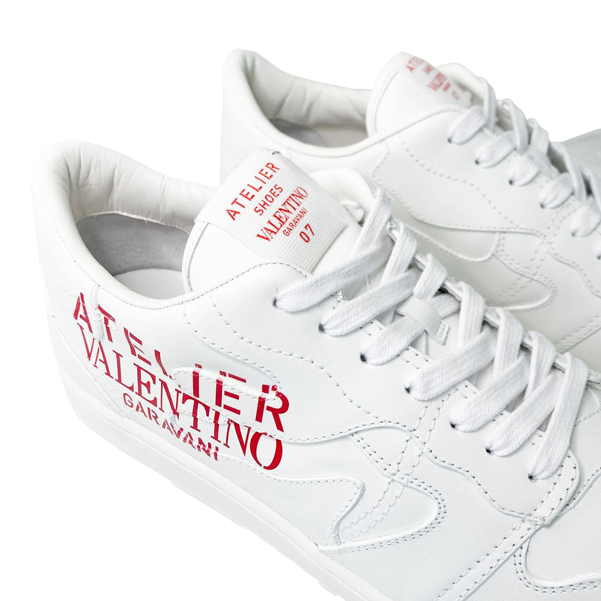Close-up angled view of the heel and side logo print on white Valentino Garavani low-tops.