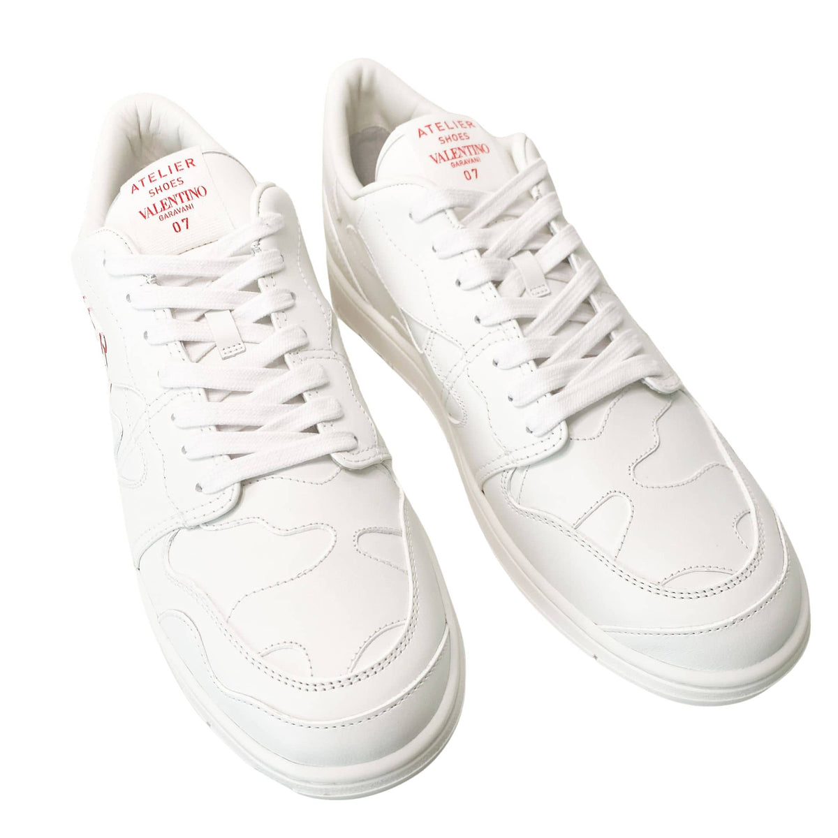 Three-quarter top view of white Valentino Garavani men's low-top leather sneakers.