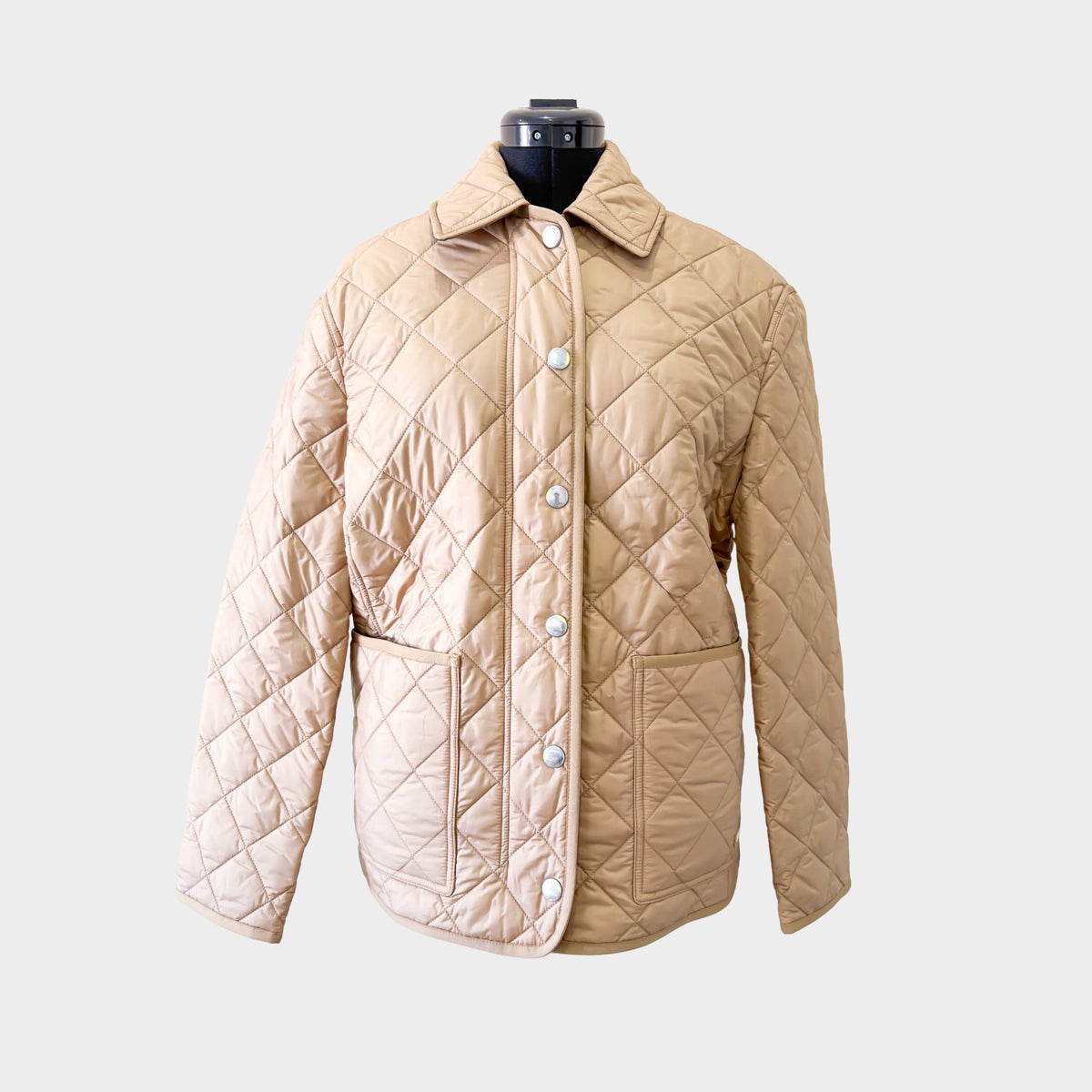 Front view of the luxury Burberry Dalry quilted jacket in a classic camel colorway, showcased on a display mannequin.