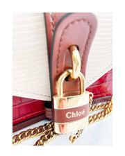 Close-up view of the Chloé Aby chain bag, highlighting the signature gold-tone padlock embellishment and textured leather panels.