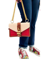 Full-length studio view of a model styling the red and pink Chloé Aby shoulder bag with a casual outfit and sneakers.
