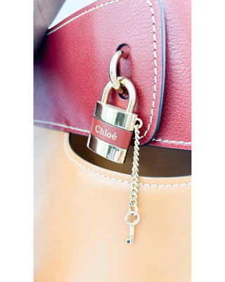 Close-up of Chloé Aby Day bucket bag in autumnal brown showing lock and leather detail