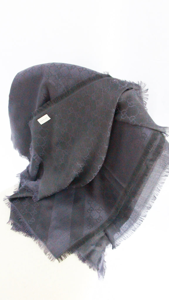 Folded view of navy Gucci GG monogram scarf displaying jacquard woven silk wool fabric texture.