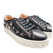 Side profile of Aquazzura Cosmic - 36 Star low-top sneakers in black leather, featuring metallic star studs on the upper and embossed star patterns on the white platform sole.