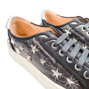 Side profile of Aquazzura Cosmic Star low-top sneakers in black leather, featuring metallic star studs on the upper and embossed star patterns on the white platform sole.