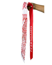 Flat lay view of the red and white Ferragamo foliage silk twilly scarf looped across a clean background.
