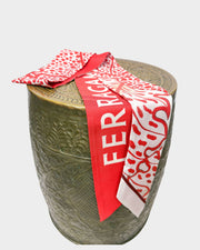 Salvatore Ferragamo red foliage print silk twill scarf wrapped around a neutral textured cylinder display stand.