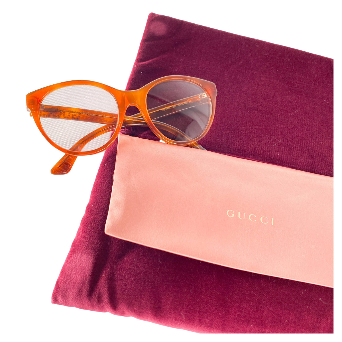 Gucci light brown crystal logo sunglasses displayed with magenta velvet hard case, satin pouch, and microfibre cloth