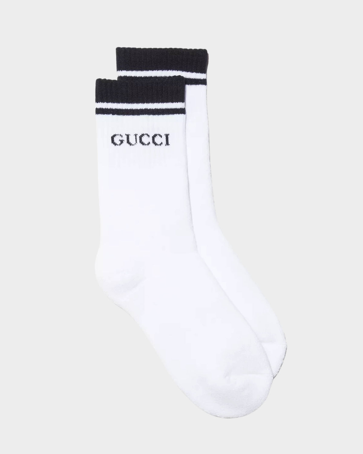 Front view of white Gucci cotton tennis socks featuring black athletic top stripes and iconic Gucci block letter logo