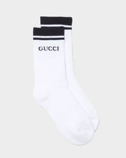 Front view of white Gucci cotton tennis socks featuring black athletic top stripes and iconic Gucci block letter logo