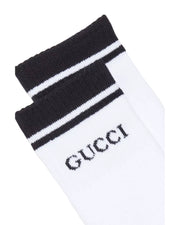 Close-up angled view of white Gucci logo striped tennis socks showing ribbed cuff texture and designer logo detail