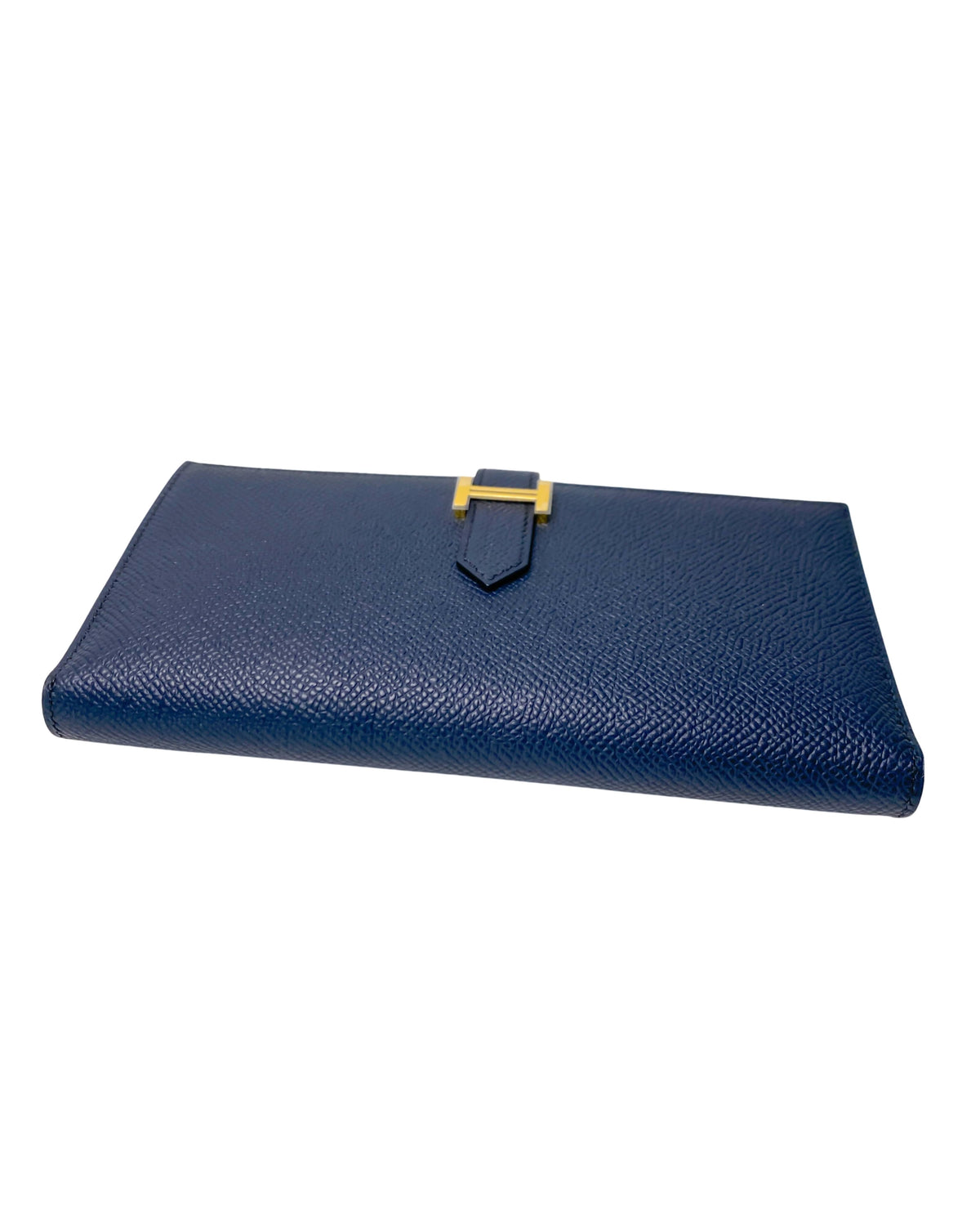 Three-quarter view of Hermès Bearn Soufflet wallet in Blue Indigo highlighting its sleek, slim profile and gusseted expansion design.