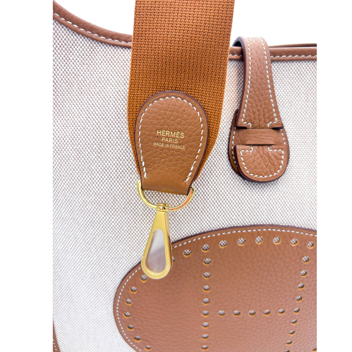 Close-up detail of yellow gold-plated metallic ring hardware and leather attachment on the Hermès Evelyne III 29 bag.