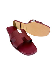 Bottom sole and underfoot view of Hermès Oran sandals in Framboise leather showing natural leather outsole craftsmanship.