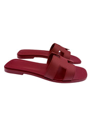 Side profile view of Hermès Oran flat slide sandals in Framboise leather highlighting the low flat heel and clean silhouette.