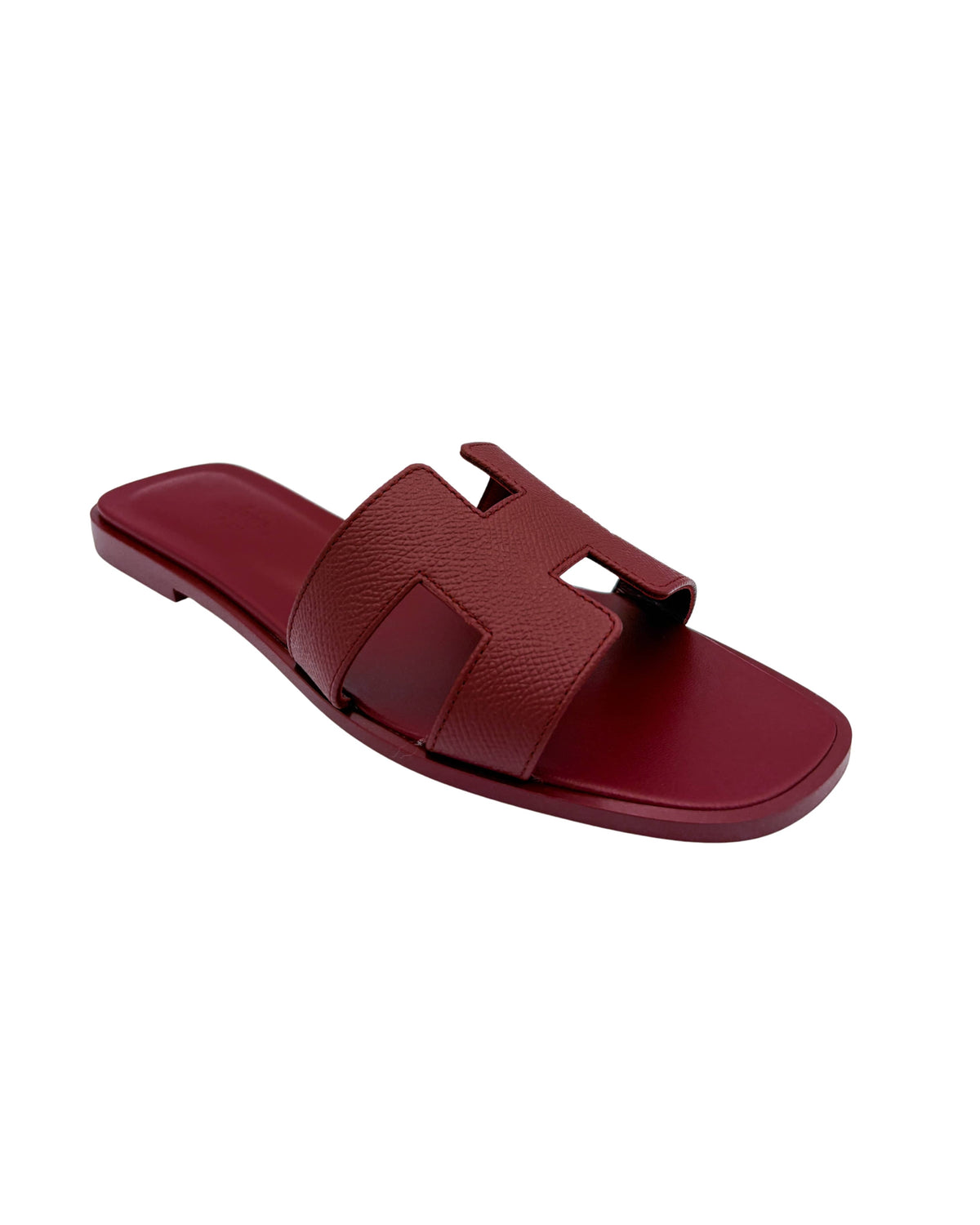 Angled single shoe perspective of Hermès Oran sandal in Framboise leather detailing the rich pink grain and craftsmanship.