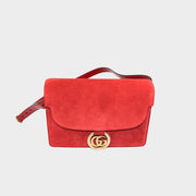 Front view of the luxury Gucci GG Ring shoulder bag in rich red suede, highlighting the signature gold GG logo hardware.