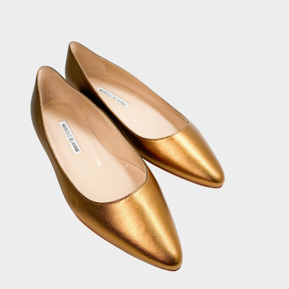 Pair of Manolo Blahnik BB Flat shoes in metallic gold leather featuring a classic pointed toe box profile.