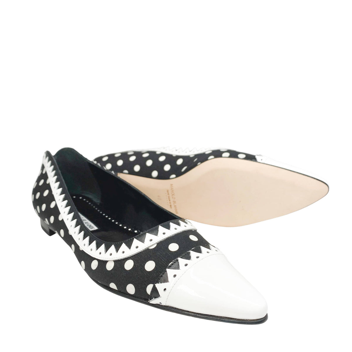 Angled view of a pair of Manolo Blahnik Elaphiria flats showing the beige leather insoles and contrasting white pointed toes.