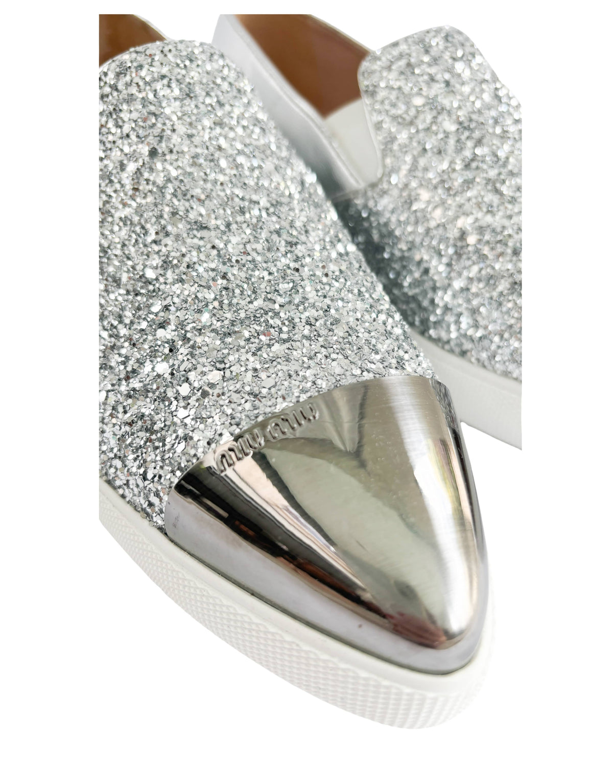 Close-up of Miu Miu pointed toe sneakers showing silver metal toe cap and sparkle detail