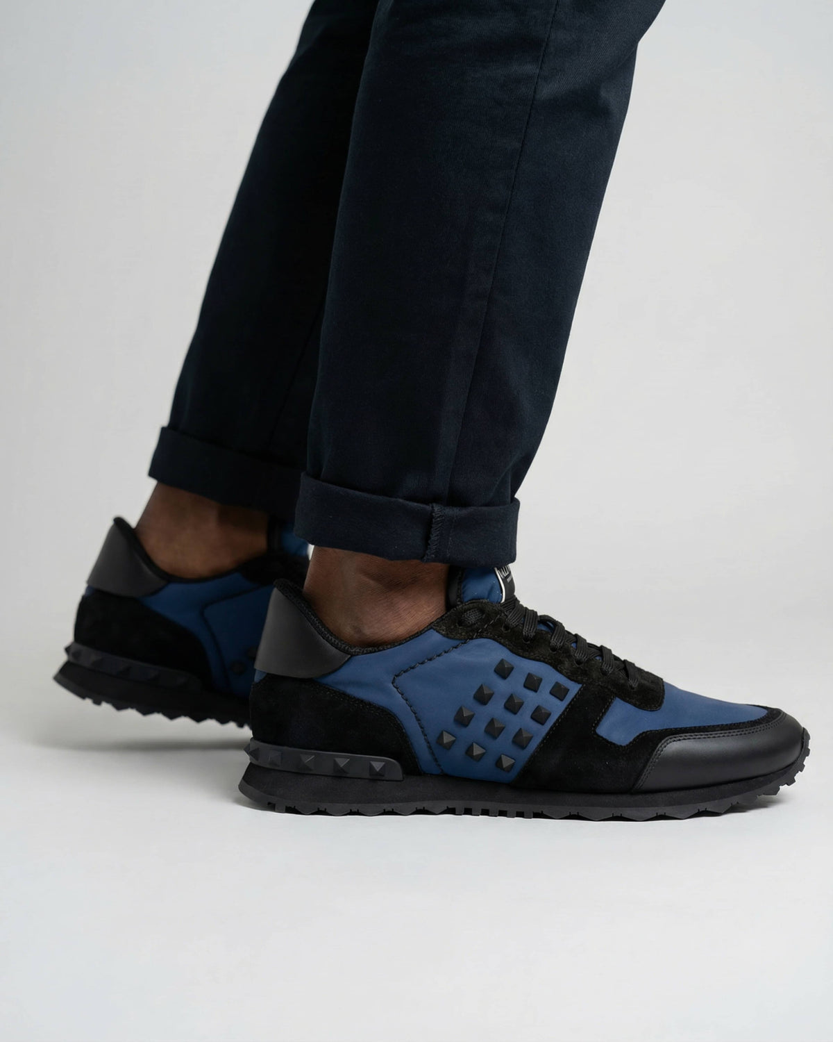 Low-angle on-foot shot of navy and black Valentino Rockrunner leather and suede trainers.