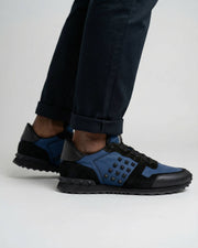 Low-angle on-foot shot of navy and black Valentino Rockrunner leather and suede trainers.