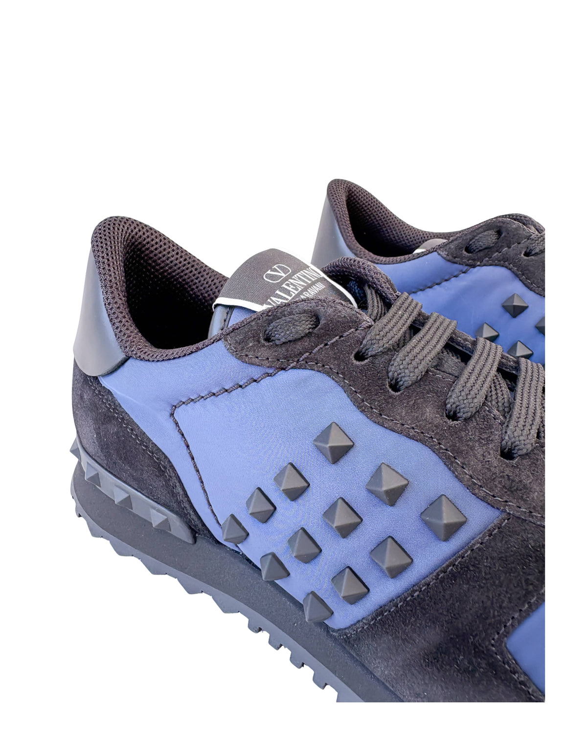 Close-up view of navy suede paneling and iconic rockstud detailing on Valentino Rockrunner sneakers.